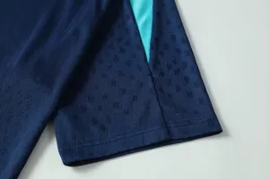 Close-up of navy blue soccer jersey sleeve with textured pattern and teal accents