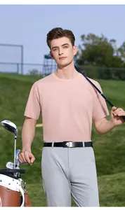Een man in een ademend roze golf-T-shirt staand op een zonnige groene golfbaan in de buitenlucht