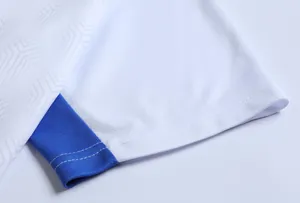 Dettaglio della manica bianca della maglia da calcio con bordo blu e mesh traspirante.