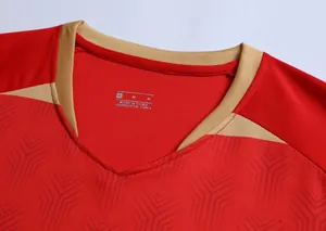 Dettaglio ravvicinato del colletto della maglia da calcio rossa con bordo dorato e texture