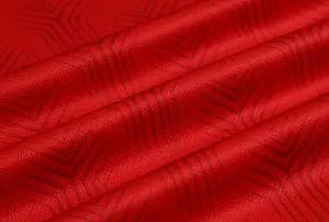 Dettaglio del tessuto mesh rosso della maglia da calcio con motivo a spina di pesce