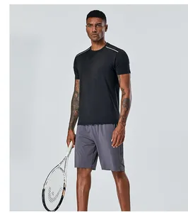 Sportif en t-shirt de sport noir et short tenant une raquette de tennis HEAD en studio.
