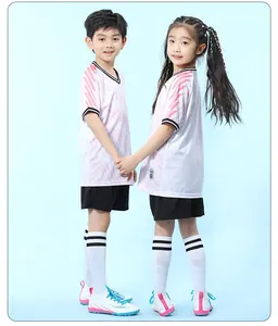 Kids soccer kit with pink gradient jersey, black shorts, and white knee socks on models.