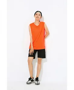 Sporty woman in orange quick-dry sleeveless tank top and black shorts for fitness