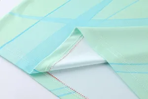 Dettaglio del tessuto mesh traspirante e dell'orlo a doppia cucitura di una maglia sportiva verde.