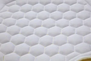 Vista macro del tessuto imbottito esagonale bianco con dettagli di cuciture gialle resistenti