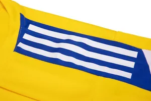 Détail de la manche d'un maillot de foot jaune avec trois bandes blanches sur bleu