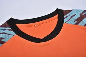 Vue détaillée de l'encolure en maille respirante d'un maillot de football orange vif.
