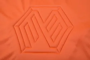 Gros plan sur le tissu du maillot de foot orange avec motif de logo géométrique embossé