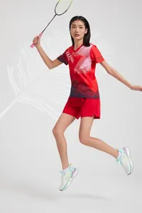 Action shot of female athlete wearing red breathable badminton jersey while jumping