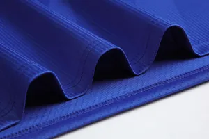Makro-Detail des atmungsaktiven blauen Mesh-Gewebes und der Nähte an einem Fußballtrikot