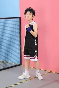 Vista completa de un niño con un conjunto de baloncesto negro con ribete rojo