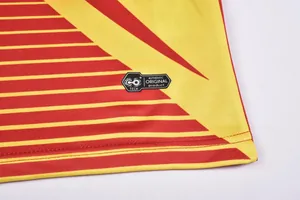 Détail du tissu du maillot de foot avec écusson CO+ TECH et rayures rouges et jaunes