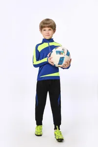 Vollansicht eines Jungen in einem blau-gelben Fußball-Trainingsanzug mit Fußball