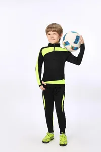 Kindermodel in einem schwarz-neongrünen Fußball-Trainingsanzug hält einen Fußball