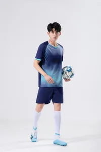 Full view of a male model wearing a blue soccer training uniform set and holding a ball