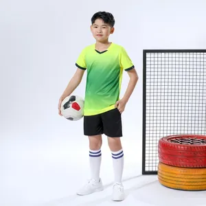 Junger Junge in einem grün-gelben Fußballtrikot mit Farbverlauf und einem Profi-Fußball