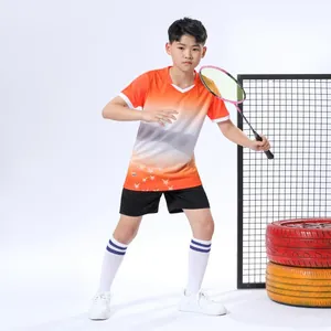 Junger Junge in orangefarbenem Sporttrikot hält einen Badmintonschläger im Studio