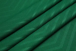 Macro detail view of emerald green checkered breathable technical fabric for football jersey
