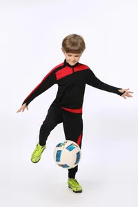 Junge im schwarz-roten Fußball-Trainingsanzug tritt gegen einen Fußball beim Training