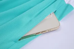 Close-up of side pocket on turquoise mesh basketball shorts holding a smartphone