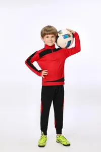 Junger Sportler im rot-schwarzen langärmeligen Fußball-Trainingsanzug für Kinder mit Ball