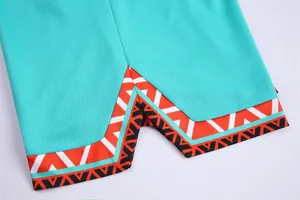 Detail view of basketball shorts hem with orange geometric pattern on teal fabric