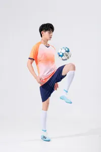Male model in vibrant orange and blue soccer training suit juggling a soccer ball