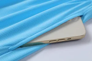 Detail showing a smartphone inside the side pocket of a light blue mesh basketball jersey.