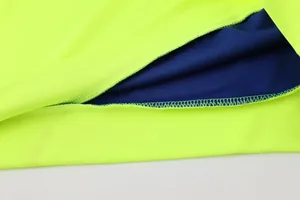 Detailaufnahme einer neongelben Fußballjacke mit hochwertigen Nähten und blauem Futter