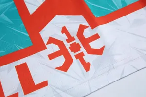 Dettaglio del tessuto mesh della maglia da basket con logo arancione e motivo geometrico.