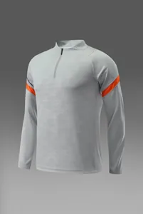 Haut de sport gris à quart de zip avec manches longues, détails orange et tissu texturé