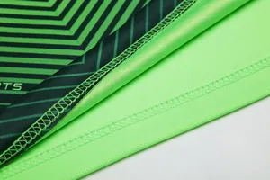 Detail view of soccer jersey hem stitching and breathable green fabric