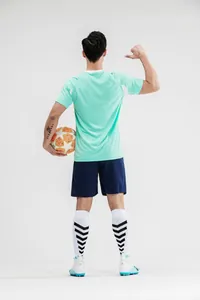 Rückansicht eines Mannes im mintgrünen Fußballtrikot-Set, der einen Ball hält.