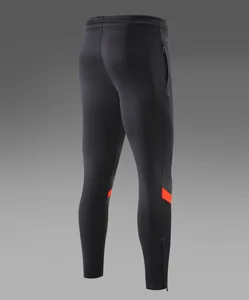 Vue arrière d'un pantalon de football noir slim fit avec détails de bandes orange.