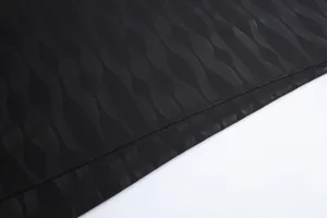 Gros plan détaillé du tissu d'un maillot de football noir avec une texture jacquard ondulée