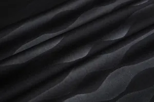 Gros plan macro d'un tissu de maillot de foot noir respirant avec un motif de vagues.