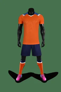 Full professional soccer kit featuring orange jersey, navy shorts and pink cleats
