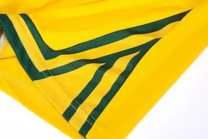 Detailed view of breathable mesh yellow basketball jersey with green striped accents.