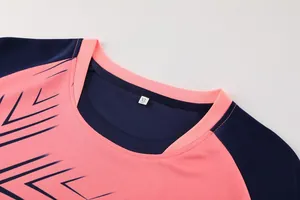 Detailopname van de halslijn van een ademend voetbalshirt in roze en navy, maat XL.