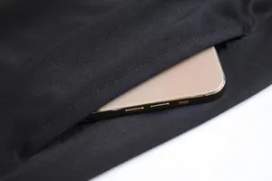 Gros plan sur le détail de la poche latérale d'un pantalon de sport noir avec smartphone.
