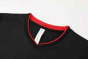 Vue détaillée du col d'un maillot de football noir avec bord rouge et étiquette XL