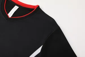Détail de l'encolure d'un maillot de football noir respirant avec bordure rouge