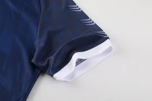Détail de la manche d'un maillot de foot bleu avec revers blancs et motif en zigzag.