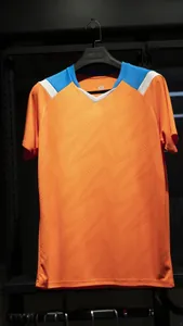 Detail view of a vibrant orange quick-dry soccer jersey with blue shoulder accents.