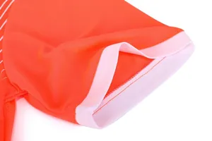 Close-up of orange football jersey sleeve with white ribbed cuff and mesh fabric.