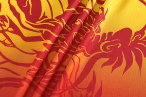 Close-up of breathable mesh fabric with vibrant red dragon pattern on yellow jersey.