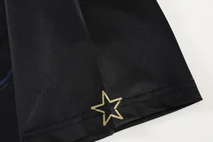 Close-up of black breathable table tennis jersey with a gold star print detail.