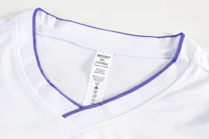 Close-up detail of the purple-trimmed V-neckline and care label on a white sports shirt