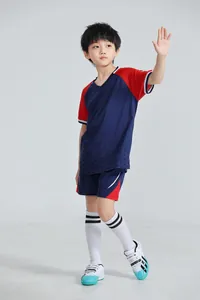 Vista de cuerpo completo de un niño con un conjunto de fútbol azul marino y rojo